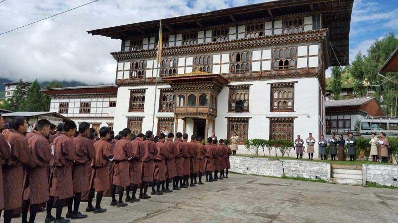 Bhutanese men in traditional gho gathered outside Tashichho Dzong