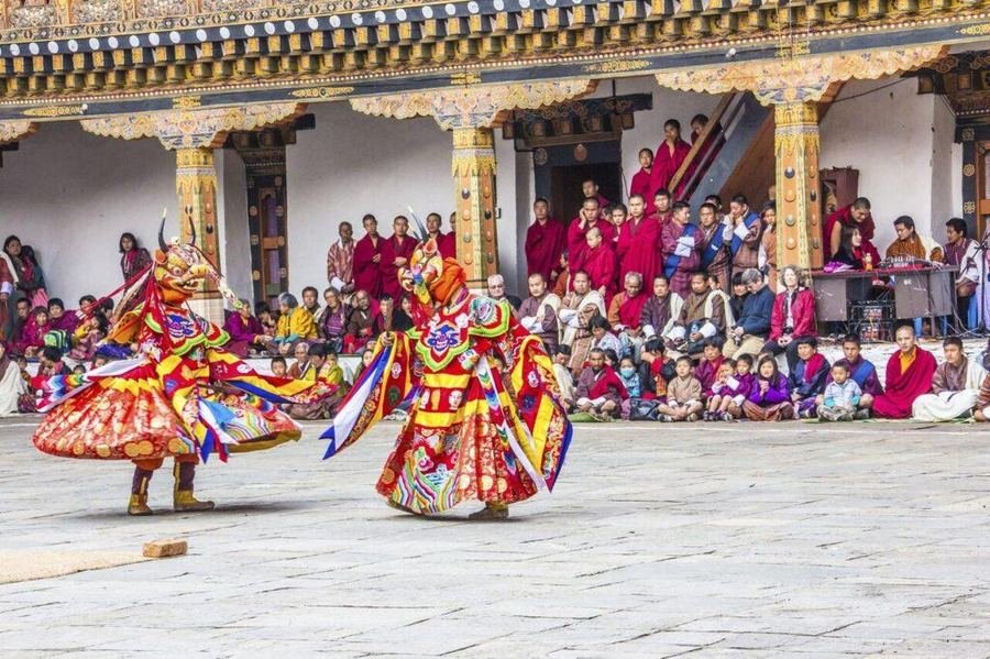 Dancers in brocade costume beneath the dzong gallery