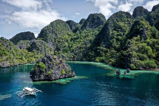 Outrigger boat between the towering limestone cliffs of Twin Lagoon