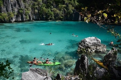 Kayakers in the clear shallows of Kayangan Lake below limestone karst