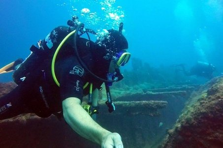 Diver descending alongside a wreck in clear blue water