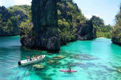 Boat and kayak on the emerald water of Big Lagoon, El Nido