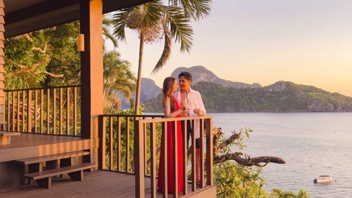 Couple on a villa balcony at sunset above Bacuit Bay