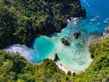 Secluded cove with turquoise shallows enclosed by karst cliffs