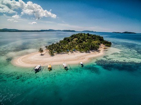 Bangka boats moored on the white sandbar of a small island near Coron