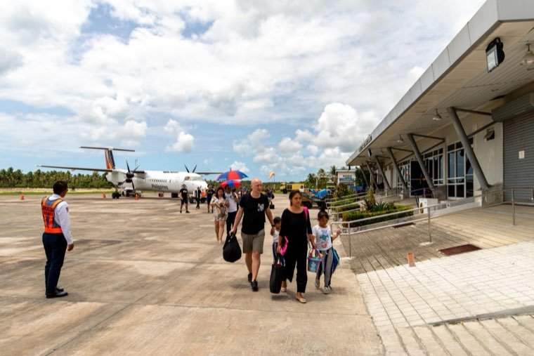 Passengers walking across the apron from a turboprop aircraft at Sayak Airport, Siargao
