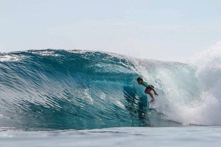 Surfer riding inside the barrel of a glassy reef wave at Cloud 9
