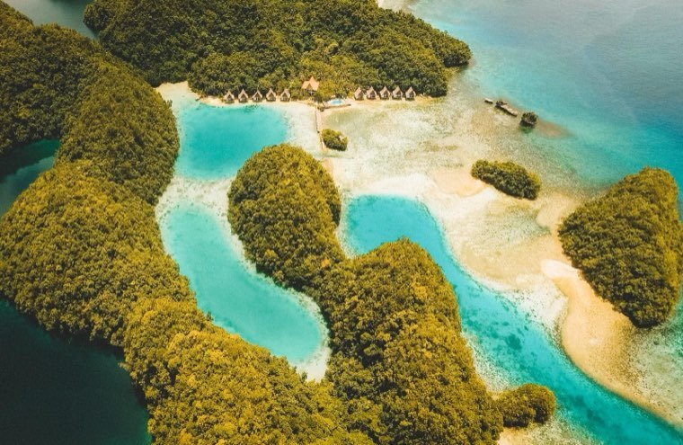 Aerial view of forested limestone islets enclosing turquoise lagoons at Sohoton Cove